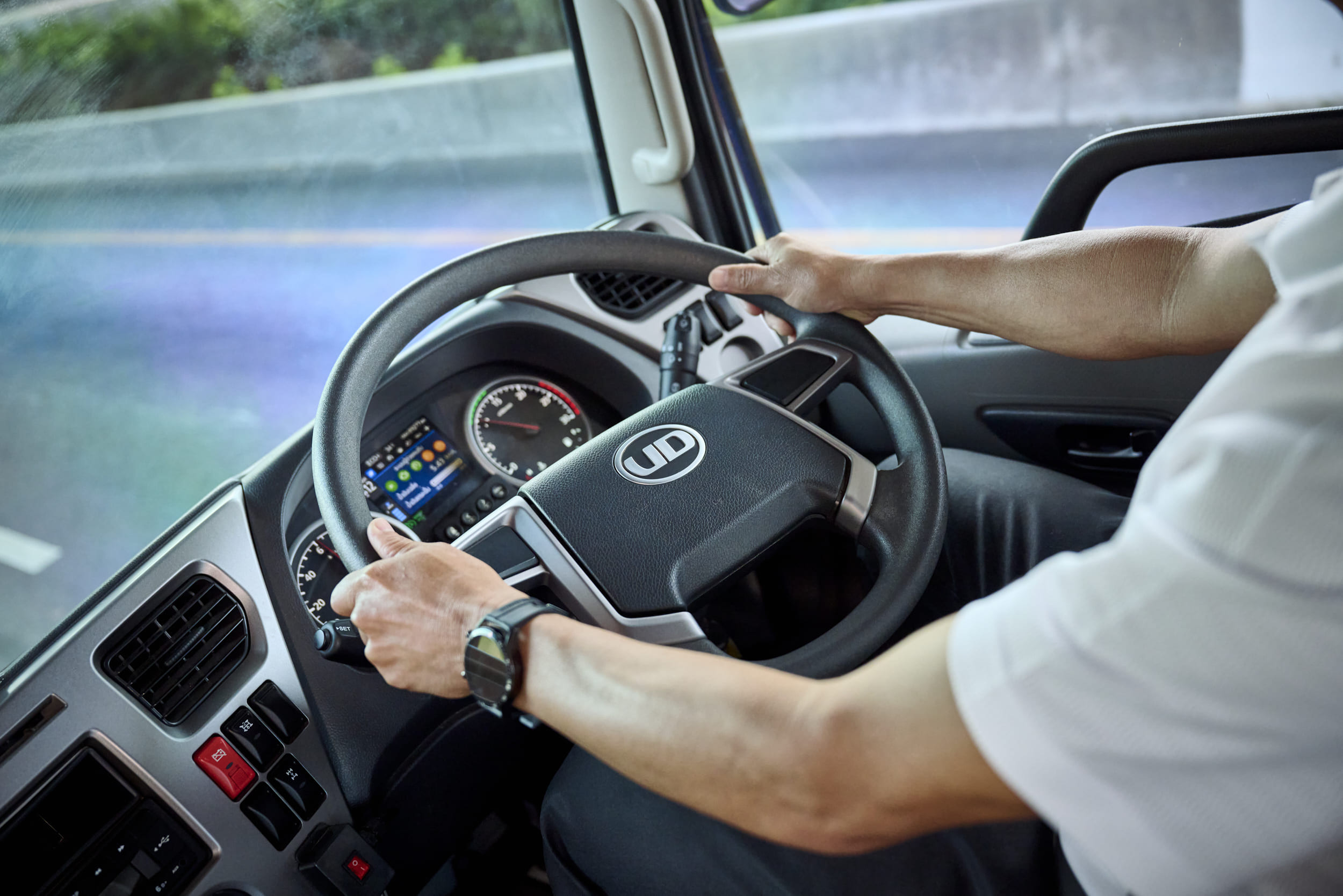 運転手が両手でトラックのハンドルを握って運転している様子