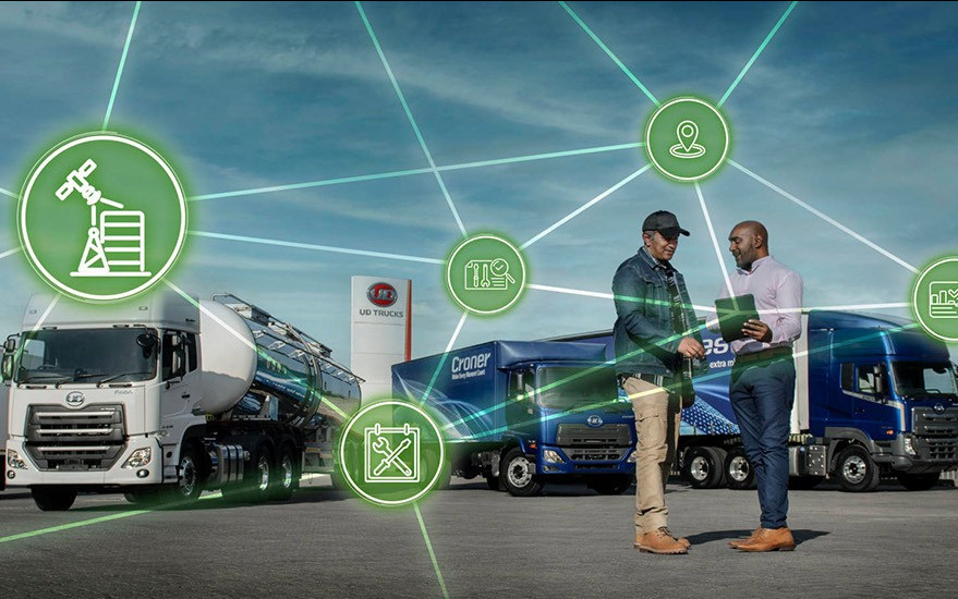 Two men shake hands in a truck yard with digital network icons overlayed.