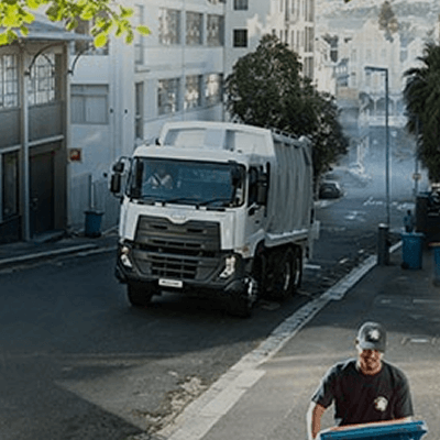 Lori ya taka barabarani, mfanyakazi wa usafi akisukuma pipa la taka pembeni.