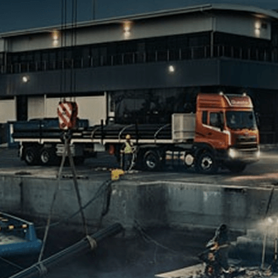 Lori la mizigo lenye rangi ya machungwa likiwa uwanjani usiku.