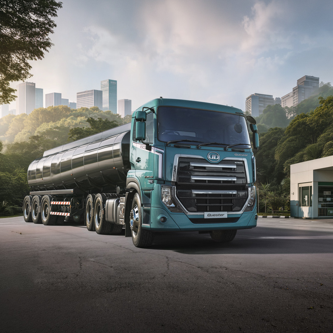 รถบรรทุกน้ำมันจอดใกล้ปั๊มน้ำมัน พื้นหลังเป็นเมืองและต้นไม้