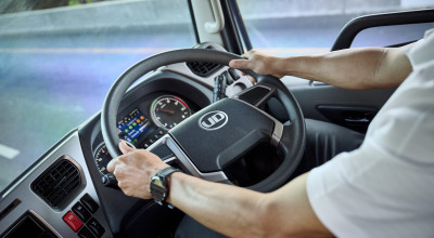 運転手が両手でトラックのハンドルを握って運転している様子