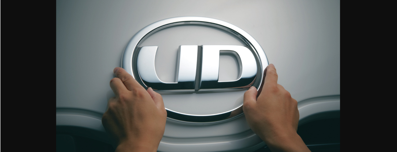 両手で触れているUDトラックスのロゴエンブレム