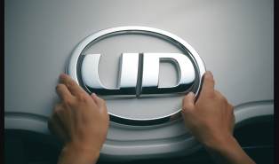 両手でUDロゴがついた車のエンブレムを触っている