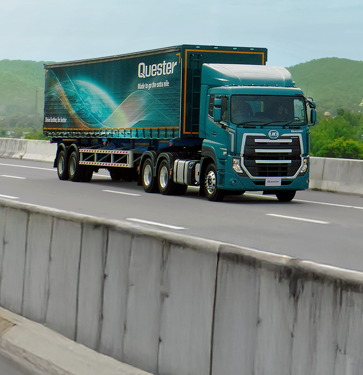 Lori kubwa ya bluu ikisafiri barabarani, milima nyuma.